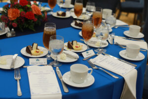 Table setting with a bright blue tablecloth and dessert and beverages.