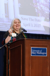 A donor speaker standing at a podium with a University of Mary Washington sign on it.