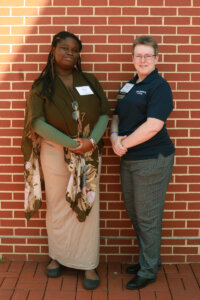 A student and donor standing in front of a brick wall.