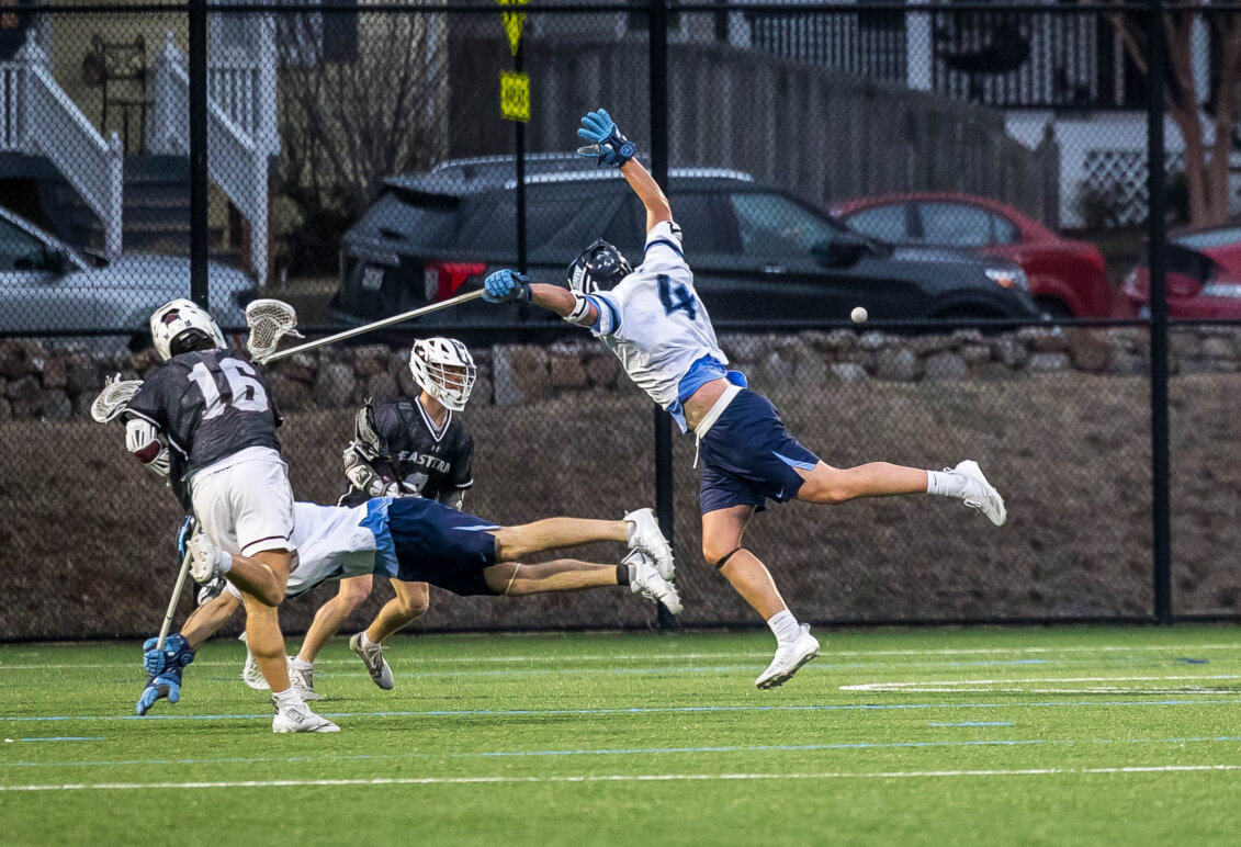 Picture of Jay Hooker playing lacrosse for UMW and jumping for a ball in defense.