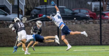 Picture of Jay Hooker playing lacrosse for UMW and jumping for a ball in defense.