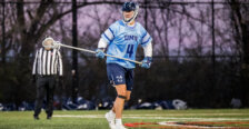 Photo of a Jay Hooker in a light blue jersey playing lacrosse for UMW holding a lacrosse stick.