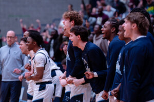 Photo of UMW men's basketball players cheering from the bench
