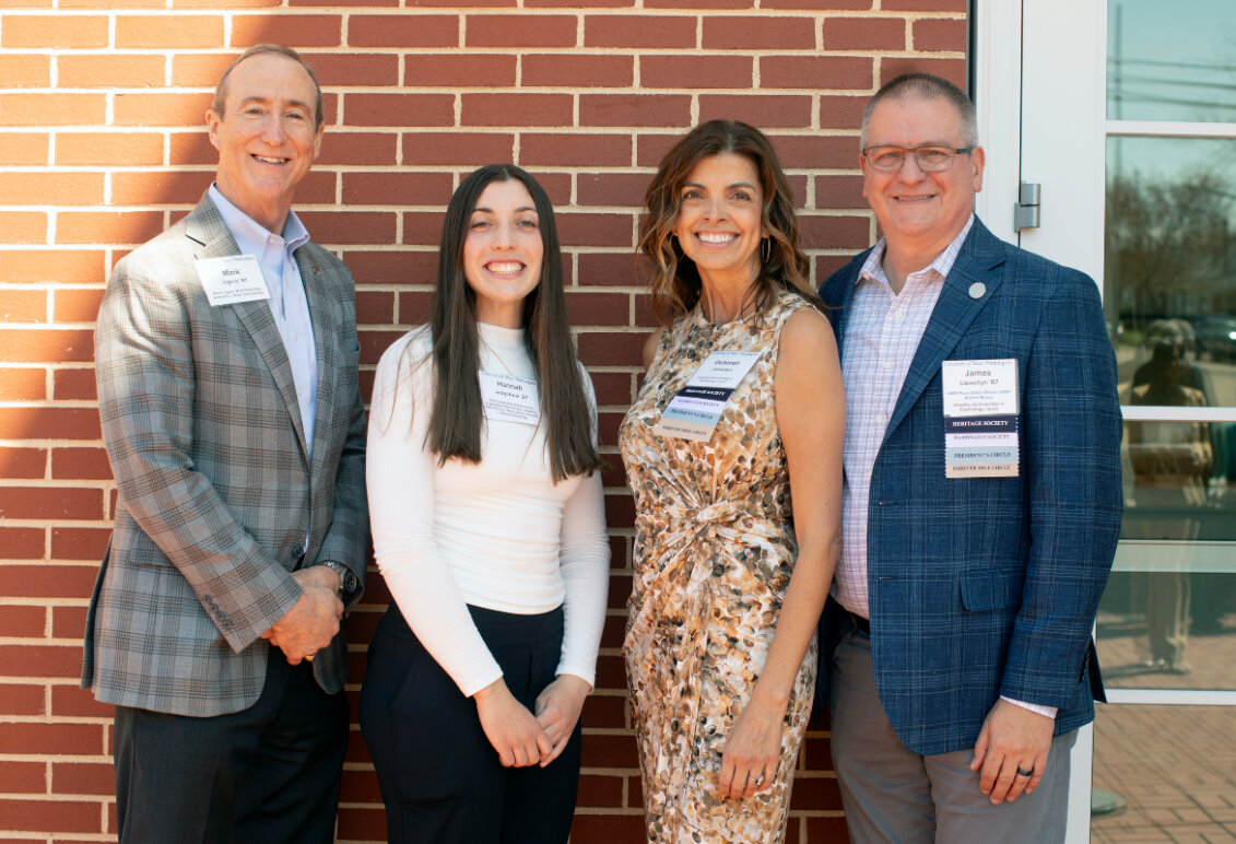 A student and three donors standing against a brick wall.