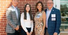 A student and three donors standing against a brick wall.