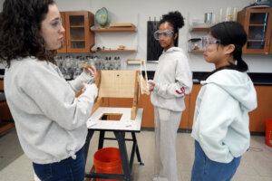Virginia Science Olympiad volunteer Claudia Meyer (left), who works in chemical safety for Amazon, discusses criteria for judging entries in the engineering category of the VASO event held last weekend at the University of Mary Washington. Lake Braddock Secondary School students Eliora Teshome (center) and Rebecca Huang spent months building a structure for the statewide competition. Photo by Suzanne Carr Rossi.