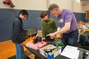 Aiden Law, 13 (left), and Oliver Sood, 13, of Cooper Middle School in McLean, get instructions from Virginia Science Oylmpiad volunteer Ian Emmons before testing their hovercraft. Photo by Suzanne Carr Rossi.
