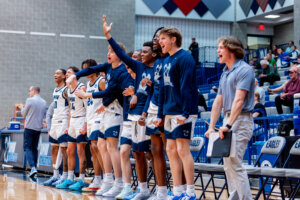 Photo of UMW basketball players standing on the sideline.