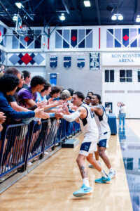 Photo of UMW basketball players celebrating with fans in the stands.