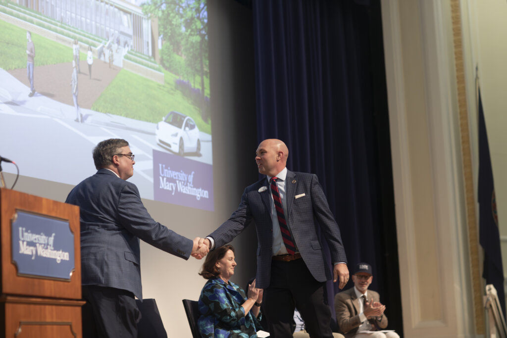 Two men shake hands onstage