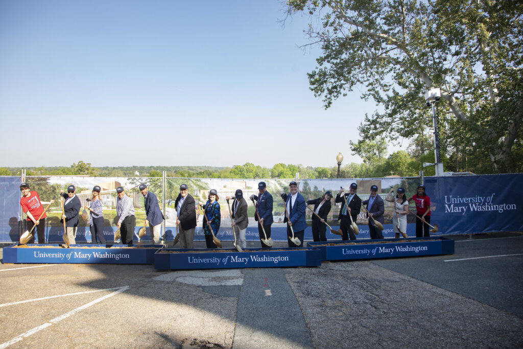 People stand in a line holding shovels