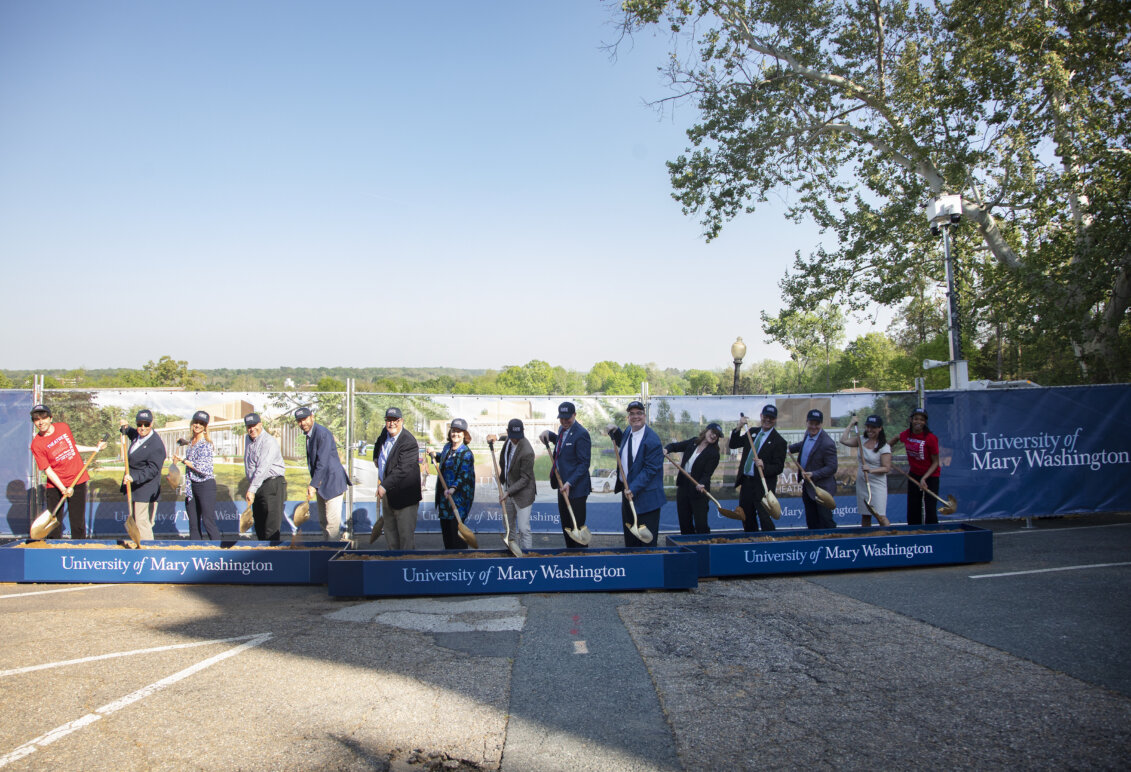 People stand in a line holding shovels