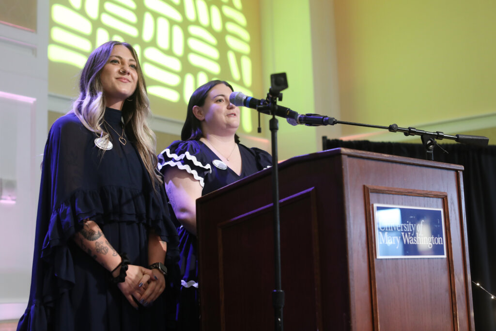 Two women stand at a podium with microphones
