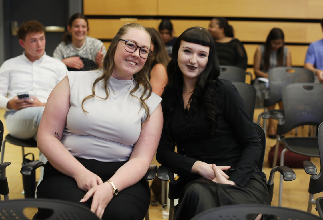 Two girls sit side-by-side smiling for the camera