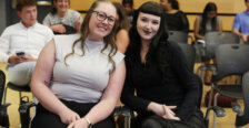 Two girls sit side-by-side smiling for the camera