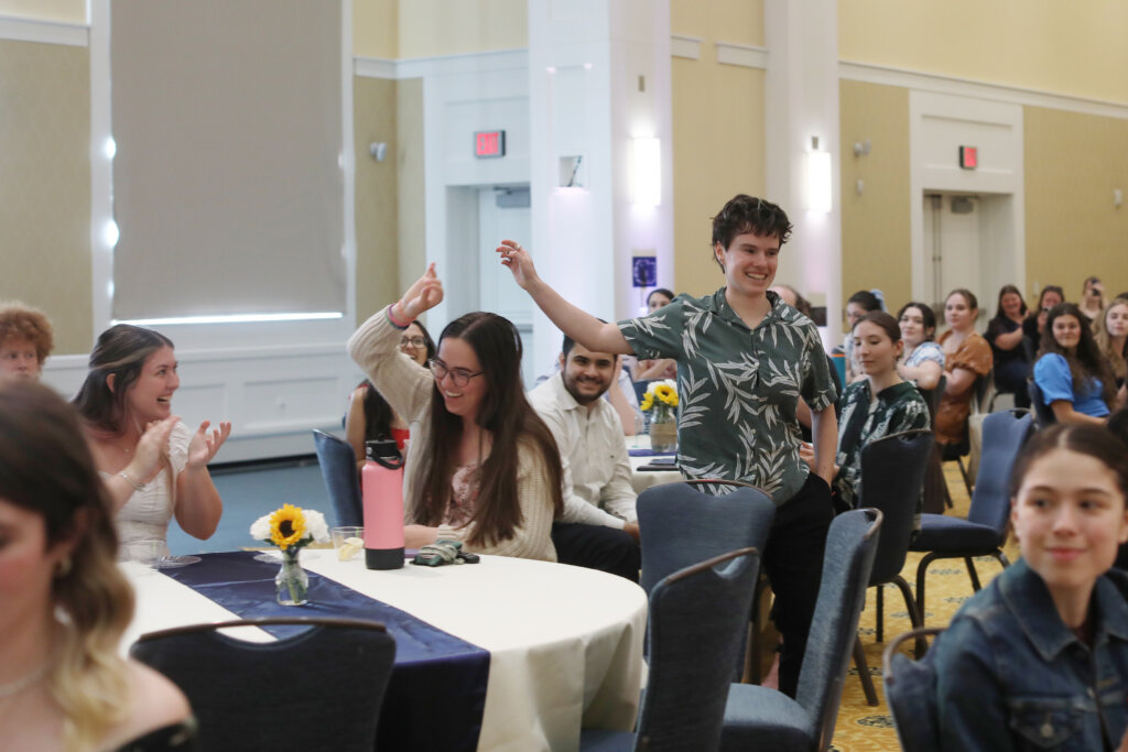 A student walks through a crowded room to accept an award