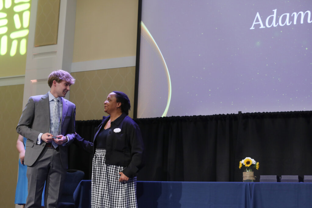 A man holding an award stands onstage with a woman
