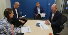 A woman and three men sit around a table with papers in front of them