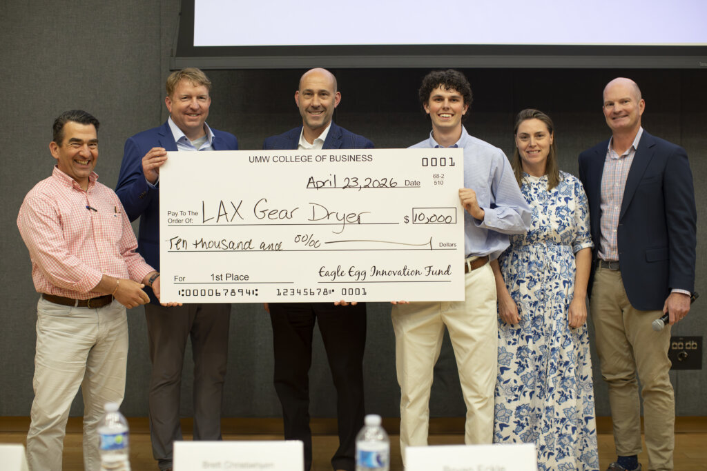 Two men stand behind a podium holding an oversized check for $10,000.