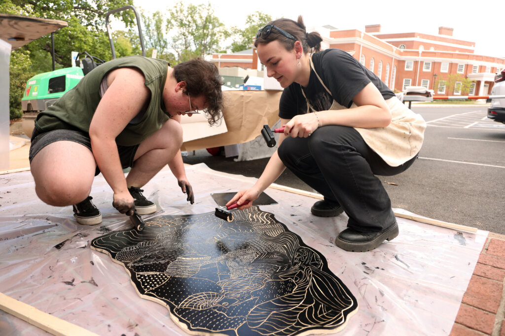 Two students ink a woodblock. 