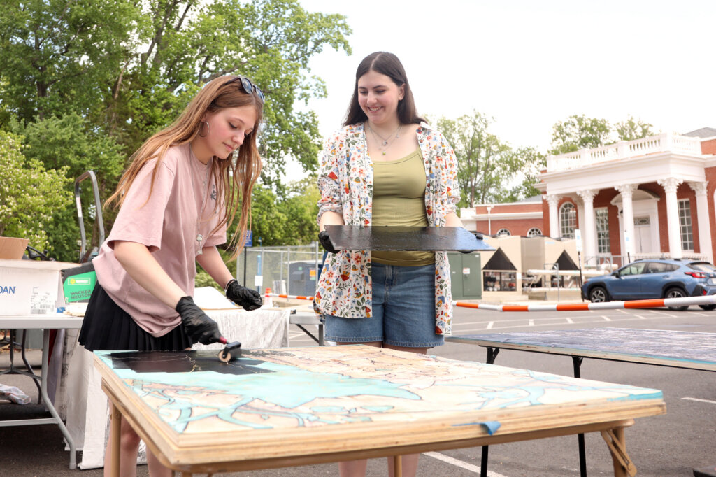 Two students sweep ink over a woodblock.