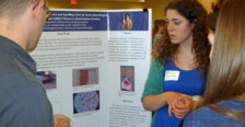 a student stands in front of a poster presenting her work