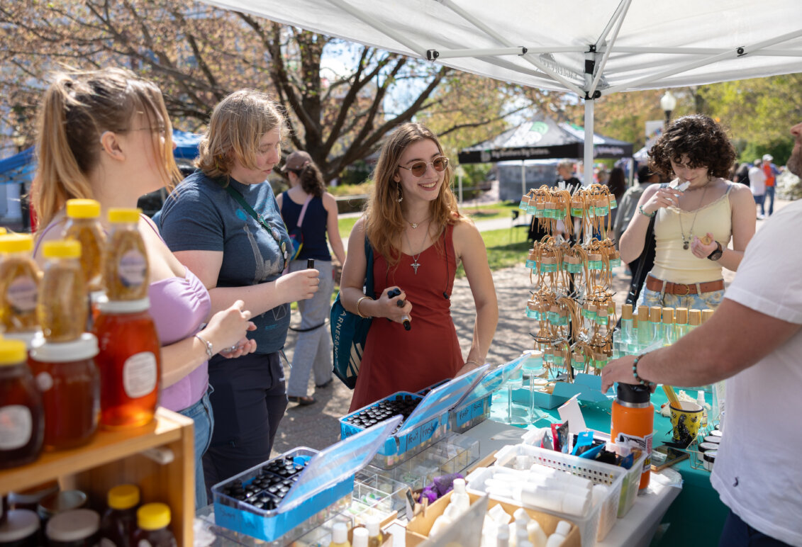 Photo of students shopping at a vendor's booth selling honey and miscellaneous items