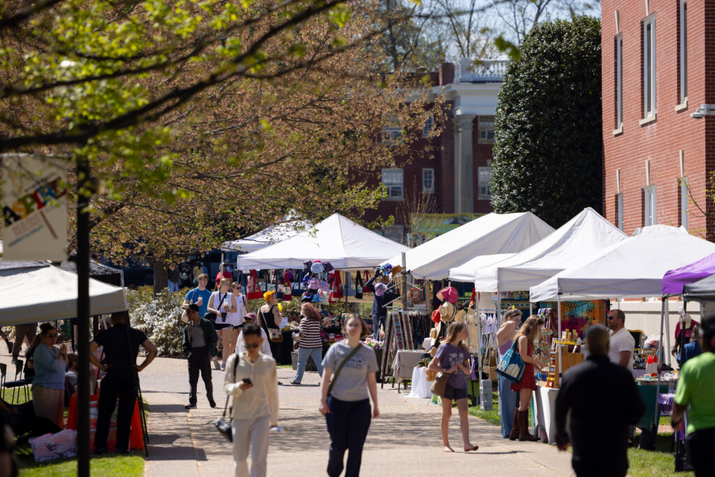 Photo of people strolling along Campus Walk where vendors have set up tents