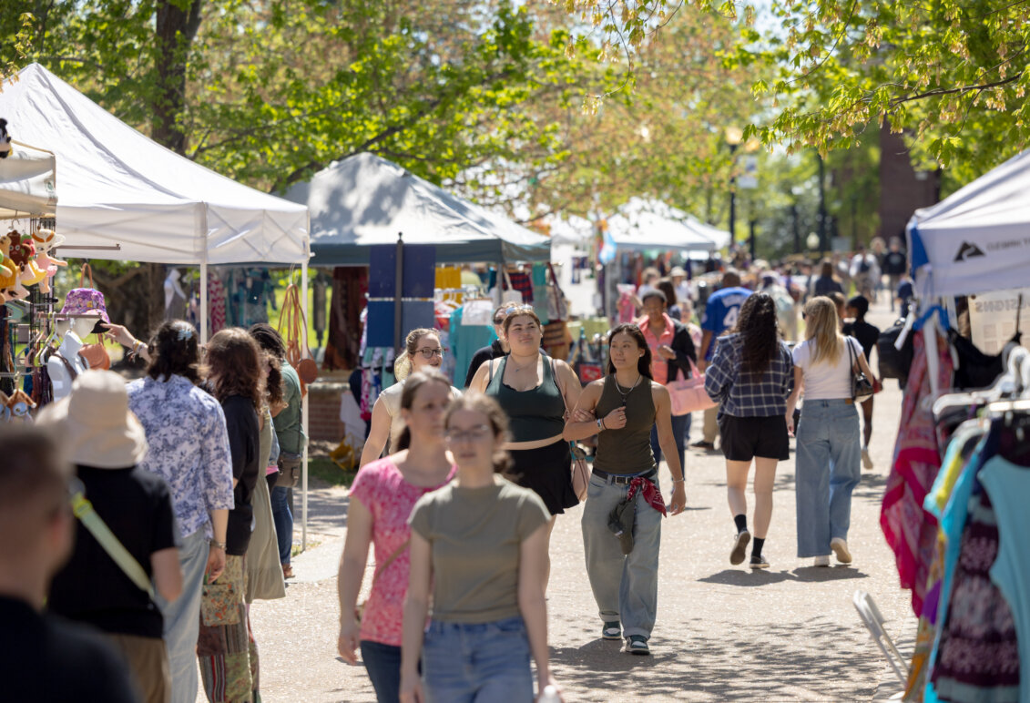 Photo of people strolling along Campus Walk, where vendors have set up tents.