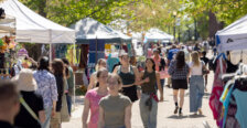 Photo of people strolling along Campus Walk, where vendors have set up tents.