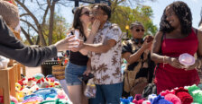 A girl kisses a boy on the cheek while some other people shop for trinkets
