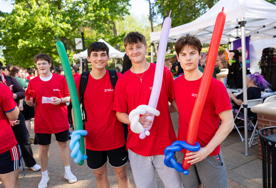 a group of guys dressed in red hold balloon swords