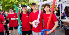a group of guys dressed in red hold balloon swords