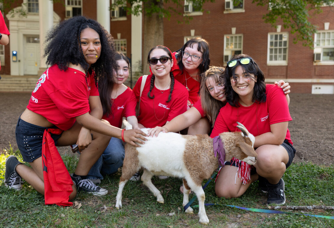 a group of girls dressed in red pet a goat