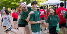 a girl jumps up on the shoulders of a guy before a crowd in the background