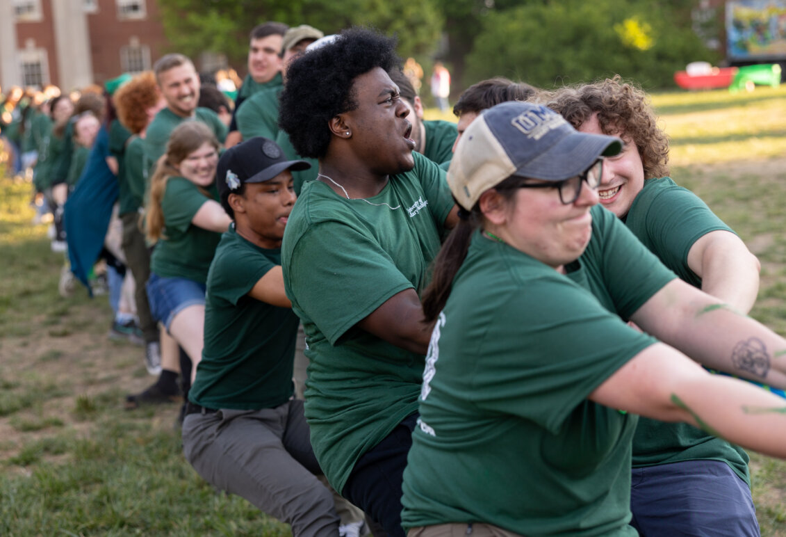 people dressed in green play tug-of-war