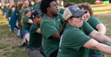 people dressed in green play tug-of-war
