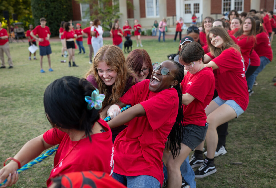 people dressed in red play tug-of-war