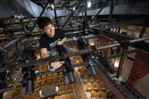 A student working on lighting in the scaffolding on a production
