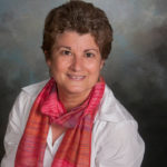 a portrait of a woman wearing a white shirt and a pink scarf