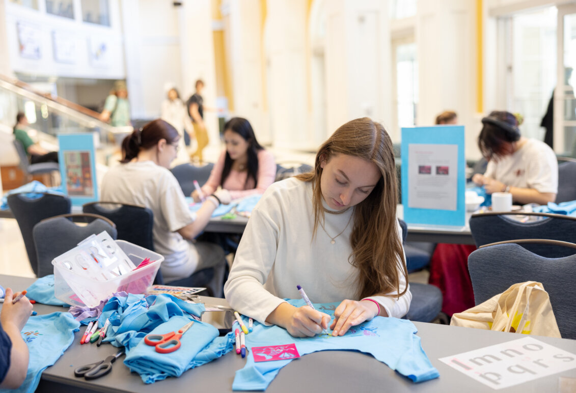 A student sits at a table making crafts