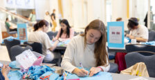 A student sits at a table making crafts