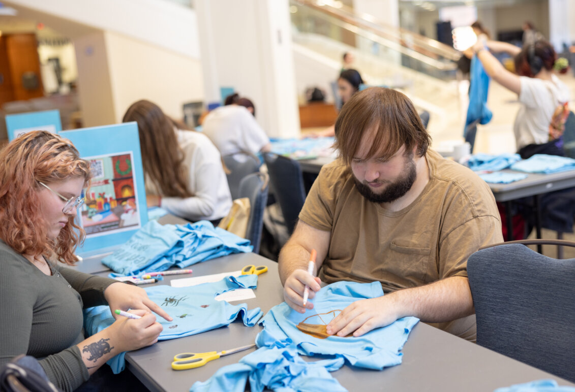 Students sit at a table making crafts