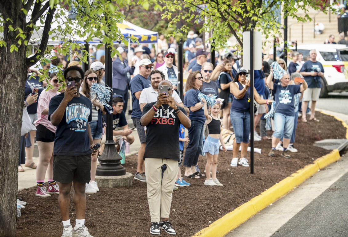 People on a city street take pictures and clap