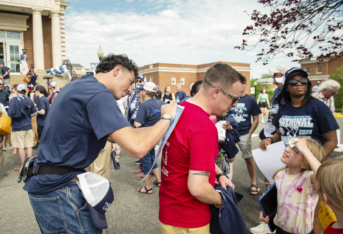 A basketball player signs an autograph using a person's back for a surface to write on