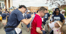 A basketball player signs an autograph using a person's back for a surface to write on