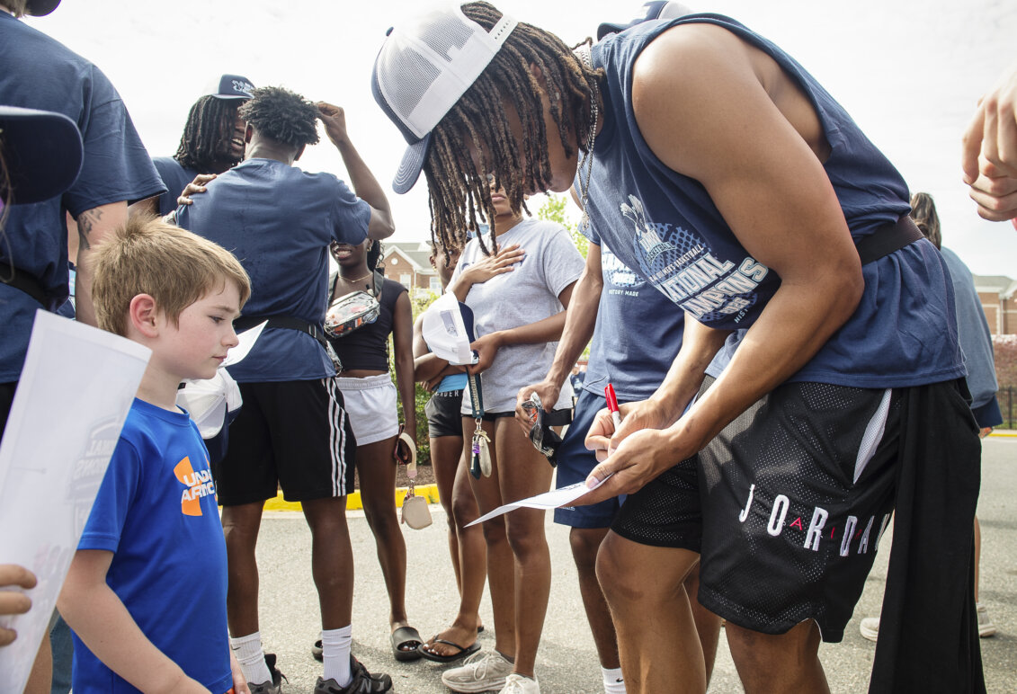 A basketball player signs an autograph for a child