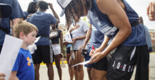 A basketball player signs an autograph for a child