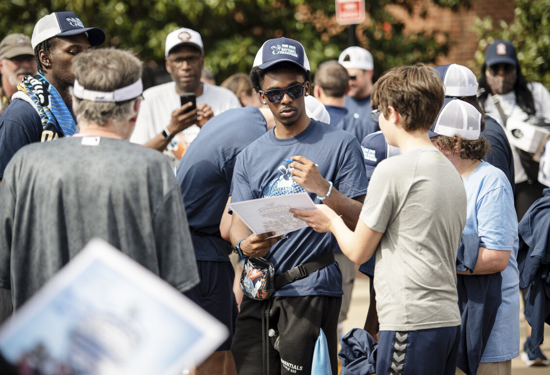 A fan asks a basketball player to autograph a poster