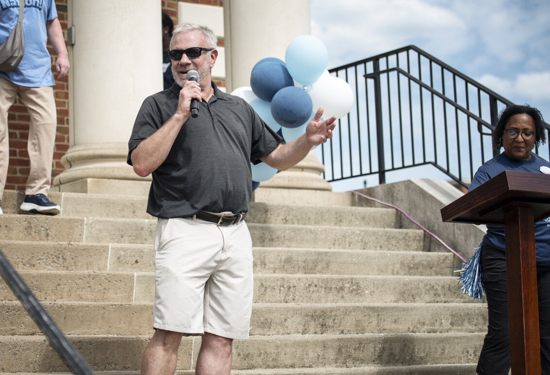 A man speaks into a microphone in front of a crowd